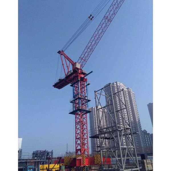 Menara derek luffing IHURMO merah besar di atas struktur bangunan menghadap langit biru.