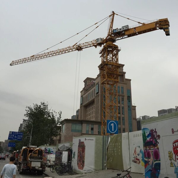 Sitio de construcción con una grúa automontable IHURMO, vallas publicitarias con arte callejero y carteles que indican una entrada de metro cercana.