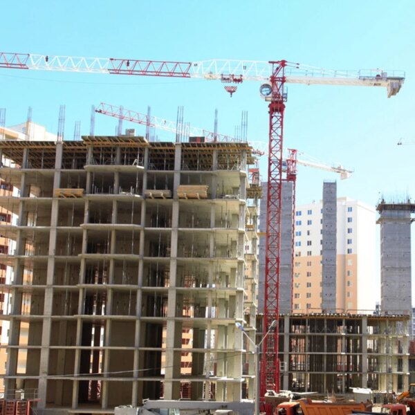 Canteiro de obras com guindastes de torre plana IHURMO de 12 toneladas e edifícios altos em desenvolvimento.