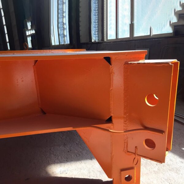 Freshly painted orange IHURMO self-erecting jib 50m QTZ63 TC5012 Tower Crane steel beam with sunlight casting shadows.