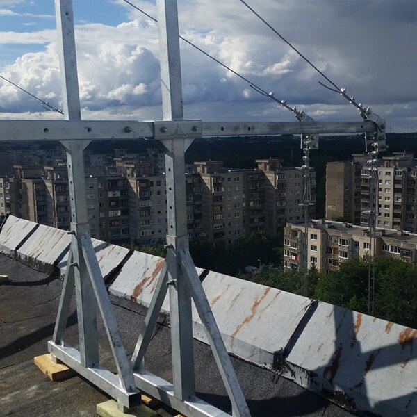 Struttura edile industriale con zincatura a caldo con cavi e piattaforma sospesa sullo sfondo di cielo nuvoloso e grattacieli.