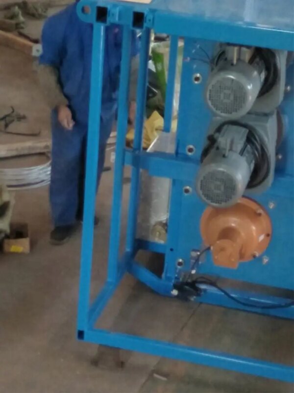 Un technicien en salopette inspecte des machines équipées de moteurs électriques sur une plate-forme élévatrice à mât unique IHURMO dans un environnement industriel.