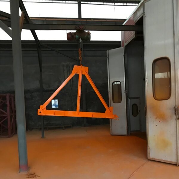 Orange industrial lifting beam hanging from a building construction pt6013-8 topless tower crane in a warehouse setting.