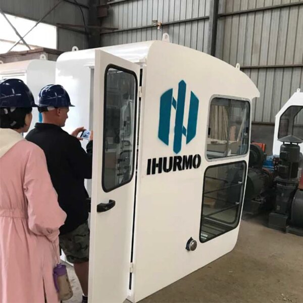 Trabalhadores inspecionando uma cabine industrial recém-fabricada com o logotipo da empresa na lateral, perto de um guindaste de torre com lança oscilante China IHURMO 8T.