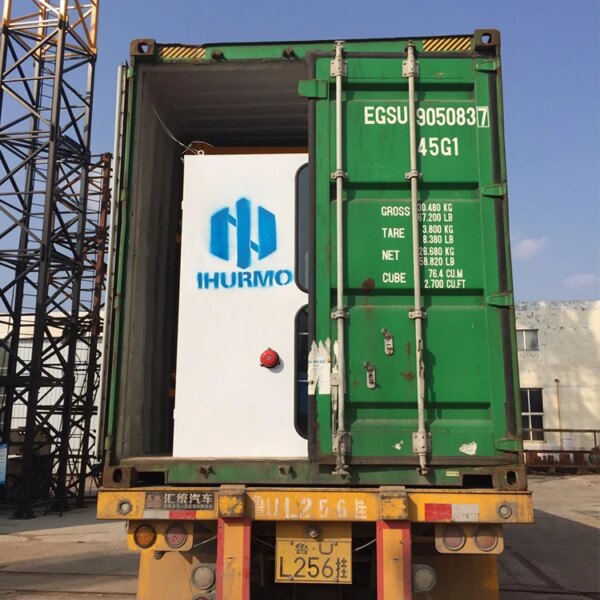 Shipping container on a transport vehicle with a company logo on the door, hoisted by a Hot sale china brand self erecting construction lift hammerhead tower crane.