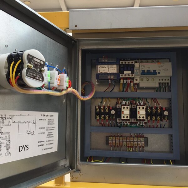 Een open elektrische schakelkast met verschillende componenten en bedrading, met een schematisch diagram bevestigd aan de deur, is gemaakt van een hangende mand van aluminiumlegering met touw voor de bouw.