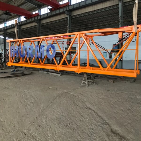 ብርቱካናማ IHURMO pt7015-10 10 ቶን 70m jib ርዝመት ከላይ-የሌለው ግንብ ክሬን "IHURMO pt7015-10" የሚል ቃል ያለው በጎን በኢንዱስትሪ መጋዘን ውስጥ ይገኛል።