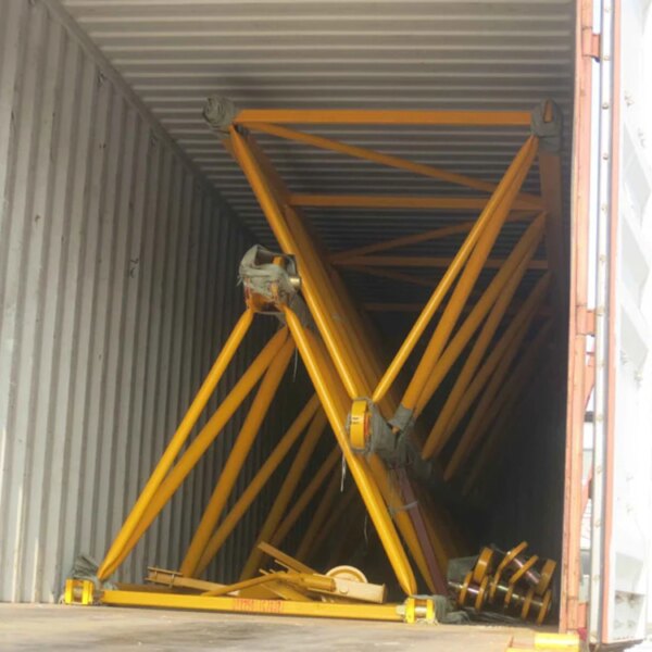 Container per spedizioni con scaffalature gialle crollate e carico dislocato, gestito da una gru a torre di sollevamento automontante IHURMO QTZ250 TC7032 da 16 tonnellate e 50 metri.