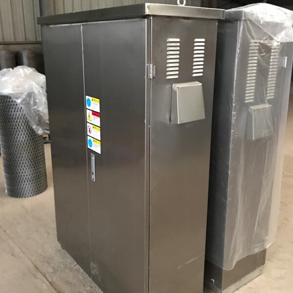 Gabinete elétrico de aço inoxidável com ranhuras de ventilação, localizado em um ambiente industrial próximo a um guindaste de torre de topo plano IHURMO de 12 toneladas com lança de 70 m para venda.