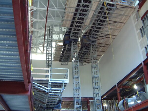 Intérieur d'un bâtiment industriel en construction avec un échafaudage monomât IHURMO et des supports structurels.