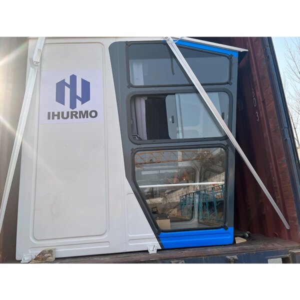 Ufficio container con una porta blu e bianca socchiusa, fissata con una cinghia bianca e servita da una gru a torre automontante IHURMO modello QTZ900 TC7082 con braccio lungo 70.