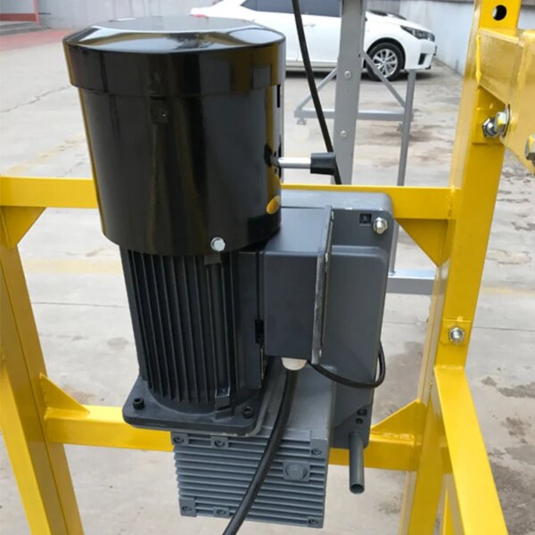 Electric motor mounted on a yellow Wholesale aluminum alloy construction hanging basket zlp 500 zlp 630 zlp 800 rope suspended access platform with an electrical junction box attached, designed for use in a ZLP 800 rope suspended access platform.