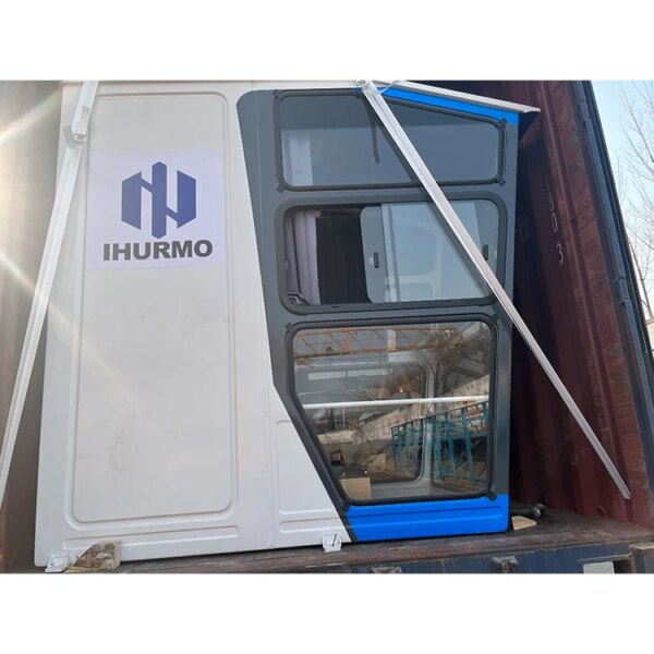 Une porte de conteneur blanche avec un logo bleu et gris, partiellement ouverte avec un aperçu de l'intérieur visible, se trouve à côté d'une grue à tour topless IHURMO pt7015-10 de 10 tonnes et d'une longueur de flèche de 70 m.