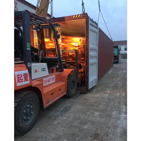 A China IHURMO 8T luffing jib tower crane loading a shipping container at dusk.