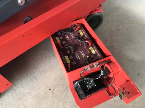 IHURMO Mobile Self Propelled Scissor Lift and charger housed in a red industrial equipment compartment.