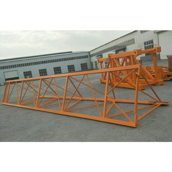 Oranje IHURMO China zelfheffende Qtz80 5613 6T hamerkoptorenkraan te koop, stalen vakwerkconstructies gelegd op betonnen grond buiten een magazijn.