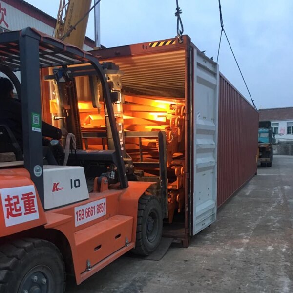 Un chariot élévateur charge des marchandises dans un conteneur d'expédition au crépuscule, supervisé par un fabricant de grue à tour de levage auto-élevable IHURMO de 16 tonnes et 50 mètres qtz250 tc7032.