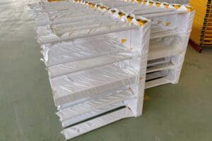 Pilhas de peças metálicas embrulhadas numa plataforma num armazém.