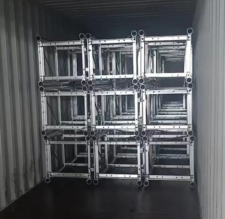 Cadrele de schele metalice bine stivuite umplu un container de transport.