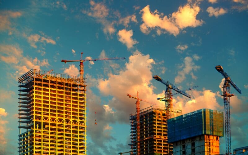 Construction of high-rise buildings against a backdrop of a sunset sky.