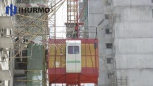 A Rack and Pinion elevator, supported by IHURMO, ensures safe, efficient transport at the busy construction site with nets and scaffolding.