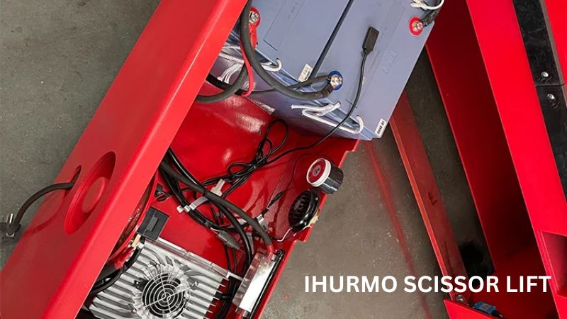 Close-up van IHURMO-liftcomponenten: gedetailleerde bedrading, accu en voedingseenheid op een rood metalen platform, perfect voor bouwliften.