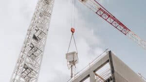 Cranes expertly hoist concrete at the site against a cloudy sky, marking the ideal spot for the tower crane.