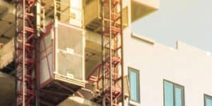 An IHURMO material hoist is mounted on a building under construction, beside upper floor windows to aid the project.