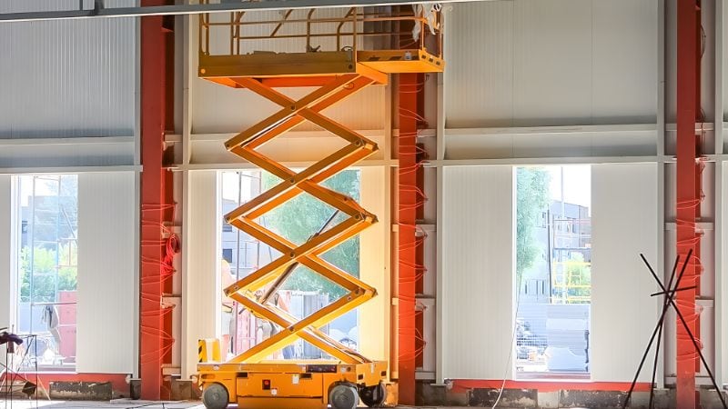 An image showcasing a scissor lift in a raised position, highlighting its mechanical components and safety features used in industrial and construction settings.