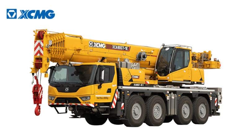 पीले रंग का XCMG क्रेन ट्रक, टेलीस्कोपिक बूम और कई धुरों के साथ, सफेद पृष्ठभूमि पर, कोने में लोगो के साथ।.
