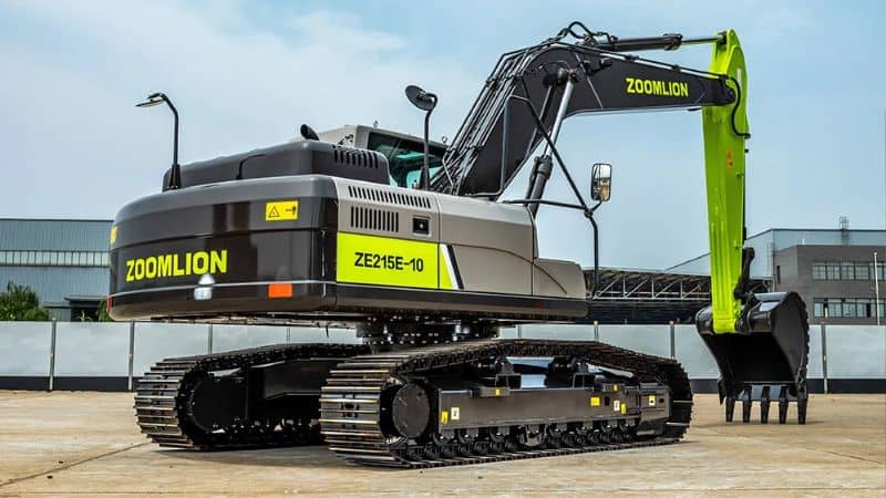 एक ज़ूमलियन ZE215E-10 उत्खनन मशीन एक औद्योगिक भवन के बाहर कंक्रीट पर खड़ी है, जो भारी भार उठाने के लिए तैयार है।.