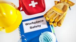 Safety gear and first aid kit arranged around a blue OSHA workplace safety manual.