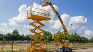 A yellow boom lift and a scissor lift are shown at a construction site, highlighting the differences between these aerial work platforms for safe and efficient access.