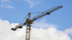 An image of a tower crane used in construction, showcasing its long jib and counterweights, essential for lifting heavy materials. The crane's structure highlights core components involved in tower cr.