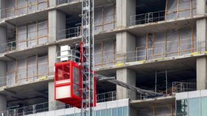 Construction hoist with safety features on a high-rise building under construction, emphasizing site controls for safety.