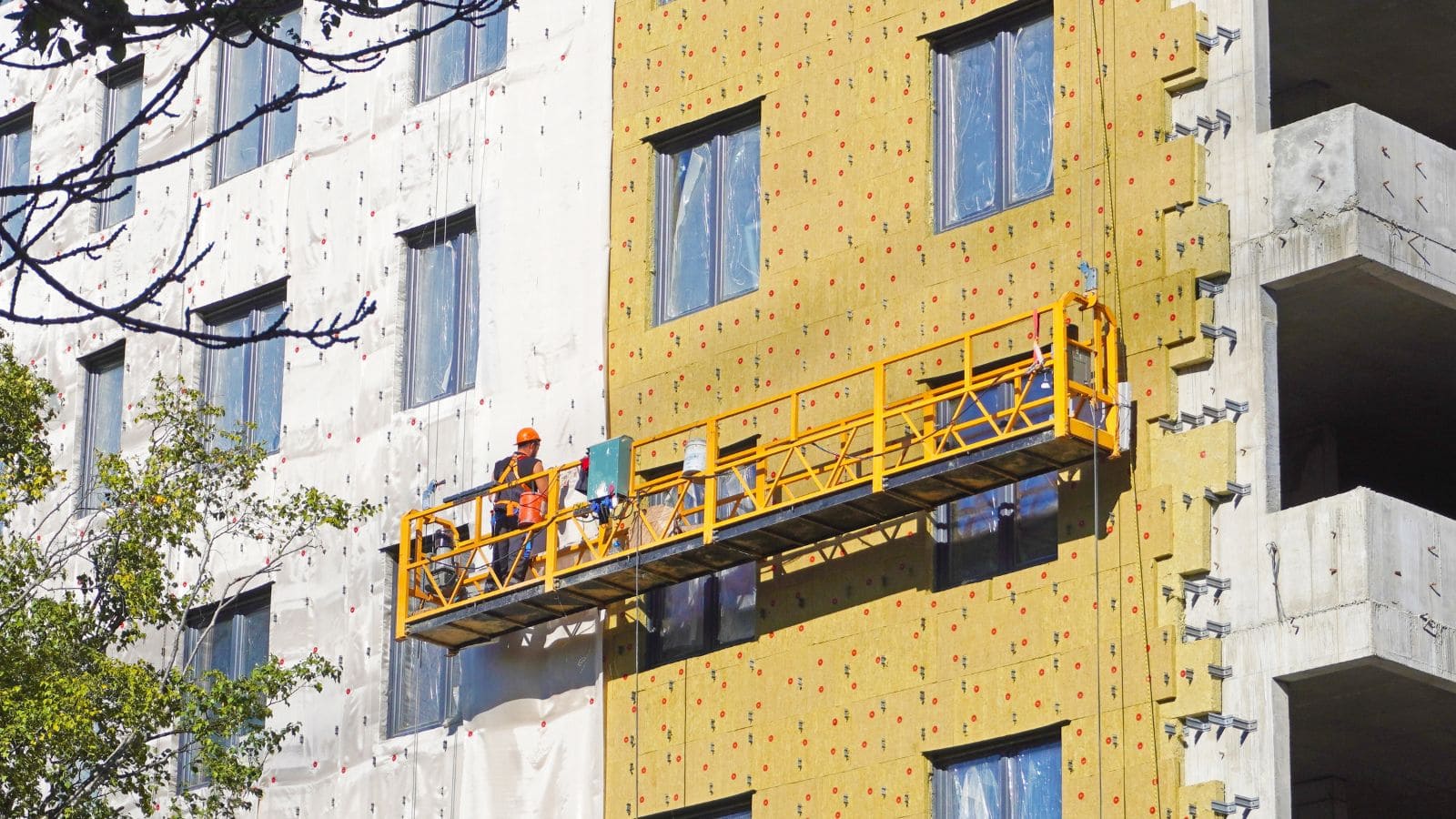 a worker with PPE working on a suspended scaffolding with proper fall prevention devices installed