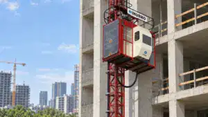 Construction elevator by IHURMO attached to a building under construction, showcasing safety features and robust design.