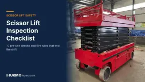 Plataforma de tijera roja autopropulsada IHURMO con la plataforma elevada en el patio de una fábrica